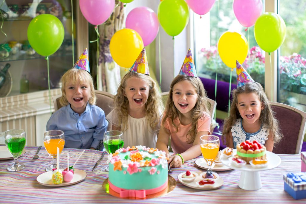 Meninas em festa de aniversário na frente da mesa do bolo