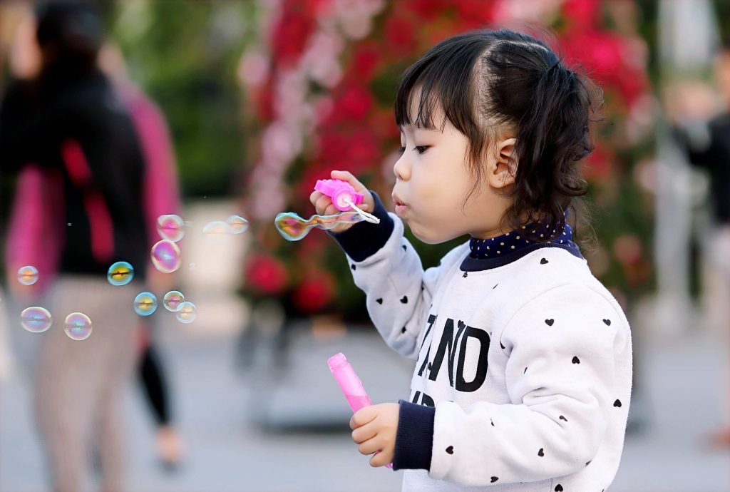 Criança asiática brincando com bolinhas de sabão
